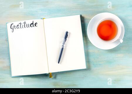 Journal de gratitude avec un stylo et une tasse de thé, tiré du haut, avec le mot écrit à la main Banque D'Images