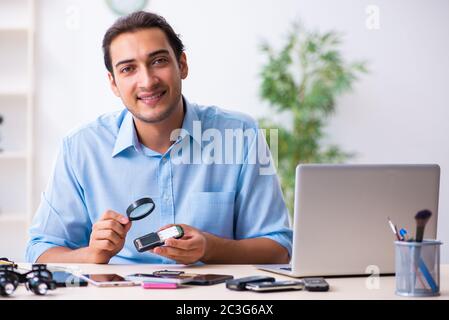 Jeune homme technicien répare le téléphone portable Banque D'Images