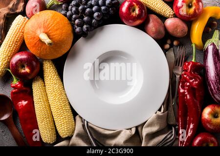 Différents légumes et fruits d'automne saisonniers avec une assiette vide sur fond gris Banque D'Images
