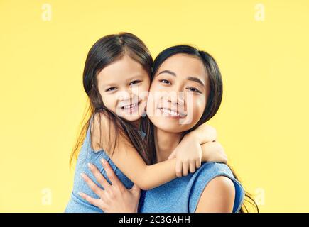 Mère heureuse et sa fille qui s'embrasse sur fond jaune. Banque D'Images