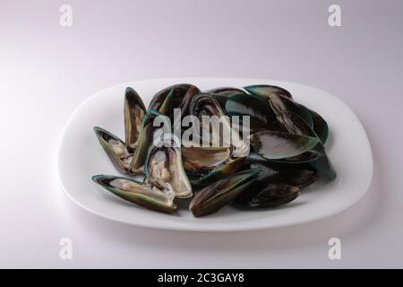 Moules crues au Kerala, poissons coquillage crus au kerala disposés dans une plaque blanche à texture ou fond blanc Banque D'Images