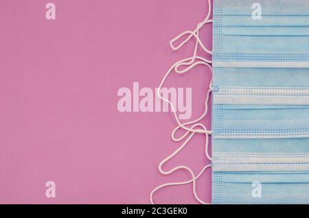 Rangée de masques chirurgicaux jetables pour couvrir la bouche et le nez et prévenir le coronavirus. Isolé sur fond rose. Soins de santé ou médical ou coron Banque D'Images