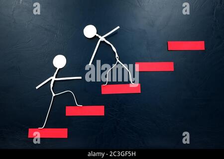 Aider la main, soutenir et travailler en équipe. Deux figurines en bâton grimpant sur une échelle rouge. Banque D'Images