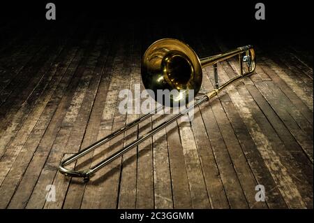 la trombone d'instrument en laiton doré se trouve sur une scène en bois brun Banque D'Images