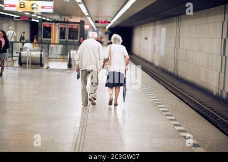 Un couple plus âgé et heureux se promenant ensemble dans la station de métro Banque D'Images