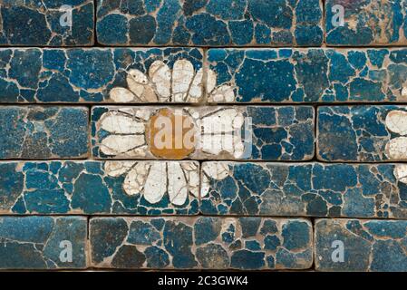 Mur de briques endommagé avec simple image de fleur de l'ancienne Babylone Banque D'Images