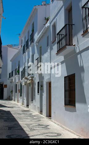 La vieille ville de Frigiliana en Andalousie, sud de l'Espagne. Maisons pittoresques de village avec balcon sur une ruelle étroite éclairée au soleil avec de longues ombres de l'après-midi Banque D'Images