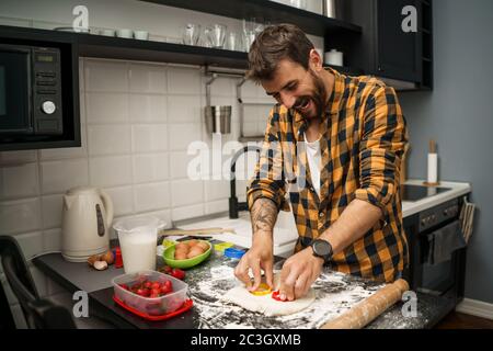 Le jeune homme fait des biscuits dans sa cuisine. Banque D'Images