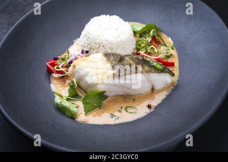 Cari thaï frit de poisson de morue de skrei gastronomique avec riz au jasmin et piment, en gros plan sur une assiette moderne Banque D'Images