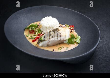 Cari thaï frit de poisson de morue de skrei gastronomique avec riz au jasmin et piment, en gros plan sur une assiette moderne avec espace pour les copies Banque D'Images