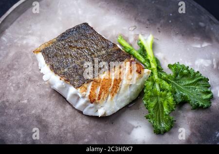 Filet de morue frite de chou frisé européen avec rabe de brocoli rapéni, sur une assiette moderne Banque D'Images