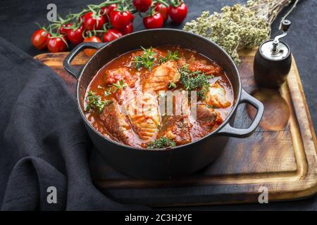 Le poisson brésilien traditionnel ragoût moqueca baiana avec filet de poisson dans une sauce tomate comme un gros plan dans un design moderne de torréfaction en fonte Banque D'Images