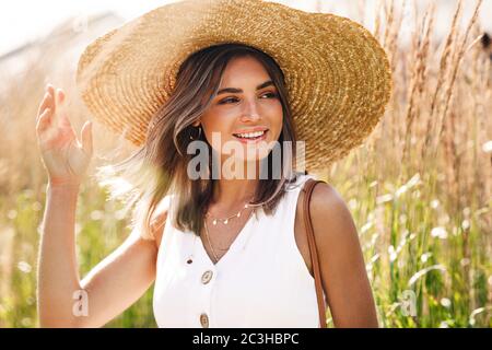 Jeune femme heureuse portant un gros chapeau de paille debout sur le terrain Banque D'Images