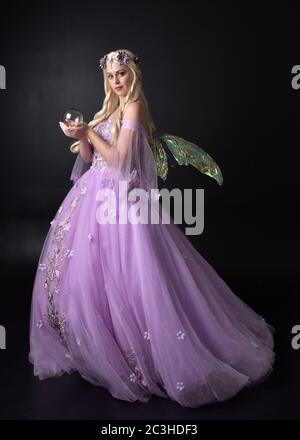 Portrait d'une belle fée blonde portant robe de fantaisie pourpre avec ailes. Posture debout pleine longueur, isolée sur un arrière-plan de studio. Banque D'Images