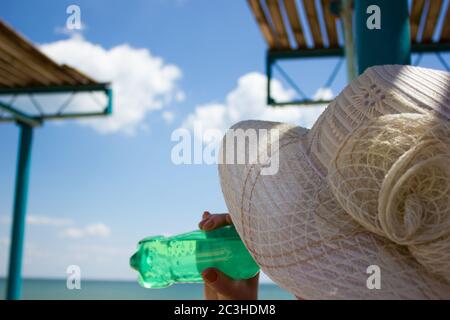 Mer eau de plage repos, femme boit l'eau paysage abri du soleil, nuages ciel Banque D'Images