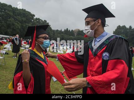 Wuhan, province chinoise de Hubei. 20 juin 2020. Patrik Silva du Cap-Vert (R) organise la tenue académique pour un diplômé lors de la cérémonie de commencement de l'Université de Wuhan à Wuhan, province de Hubei en Chine centrale, le 20 juin 2020. L'Université de Wuhan a tenu sa cérémonie de remise en fonction 2020 samedi, la plupart des diplômés assistant à la cérémonie en ligne et certains diplômés représentatifs se présentant sur place. Crédit: Xiao Yijiu/Xinhua/Alamy Live News Banque D'Images