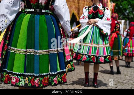 Filles vêtues de costumes folkloriques nationaux polonais de Lowicz pendant la procession de Corpus Christi. Gros plan sur les jupes traditionnelles colorées à rayures Banque D'Images