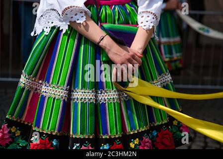 Femme vêtue de costumes folkloriques nationaux polonais de la région de Lowicz. Robe traditionnelle traditionnelle colorée à rayures et broderie fleurie Banque D'Images