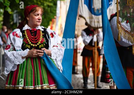 Femme vêtue de costumes folkloriques nationaux polonais de la région de Lowicz. Robe traditionnelle traditionnelle colorée à rayures et broderie fleurie Banque D'Images