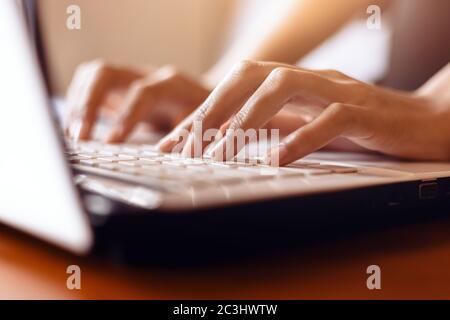 les mains de la femme tapant sur un ordinateur portable sur un bureau en bois. Banque D'Images