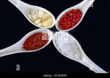 Épices, isolées. Un assortiment de safran, mastika, poivriers roses et épices en flocons de sel en cuillères blanches. Image de stock. Banque D'Images