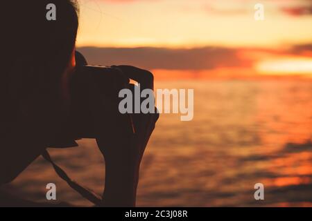 les femmes utilisent l'appareil photo pour prendre des photos de mer et de coucher de soleil entre les voyages. Banque D'Images