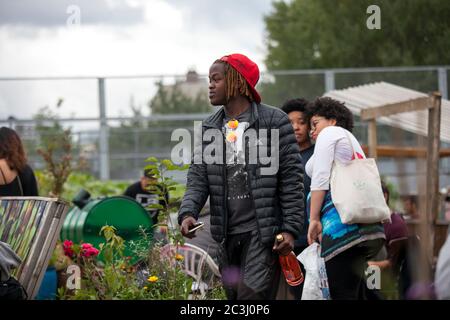 Londres, Royaume-Uni - 17 juillet 2019, jardin communautaire nomade. Fête de jardin commune. Un jeune homme en costume noir denim avec des dreadlocks se promonne autour de la ga Banque D'Images