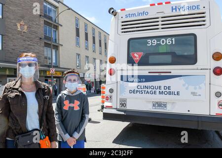 Mère et fils portant des masques protecteurs et des écrans faciaux pendant la pandémie Covid-19 debout devant la clinique mobile de dépistage gratuit Covid19, Montréal Banque D'Images