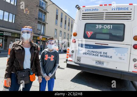 Mère et fils portant des masques protecteurs et des écrans faciaux pendant la pandémie Covid-19 debout devant la clinique mobile de dépistage gratuit Covid19, Montréal Banque D'Images