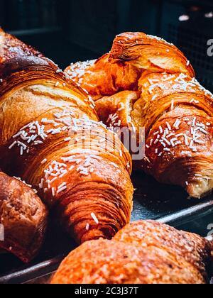 Photo verticale en grand angle de quelques délicieux croissants sur métal plateaux dans un magasin Banque D'Images