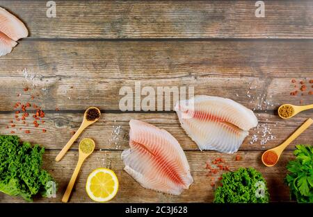 Filet de poisson non cuit de tilapia sur une table en bois avec citron et épices. Banque D'Images