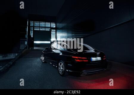 Luxueuse voiture noire la nuit avec un feu rouge allumé le sol Banque D'Images