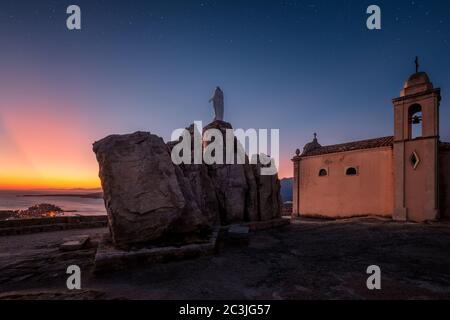 Aube se brisant sur l'église et la statue de notre Dame de la Serra au-dessus de la citadelle de Calvi dans la région de Balagne en Corse sous une nuit étoilée Banque D'Images