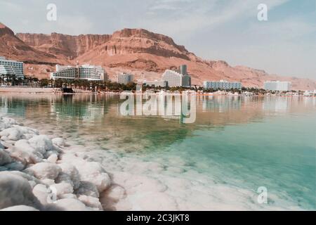 Vue sur la côte et les hôtels spa de la Mer Morte, Ein Bokek, Israël. Formations de sel au premier plan. Voyage Israël. Grands cristaux de sel. Banque D'Images