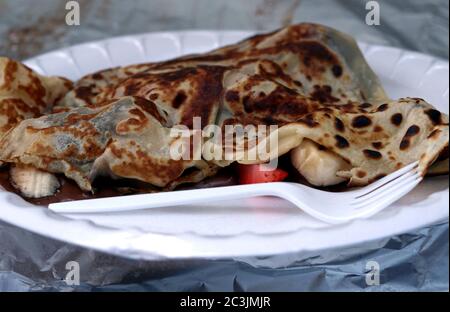 Crêpe à dessert avec de la banane, du chocolat et des fraises sur une assiette en plastique Banque D'Images
