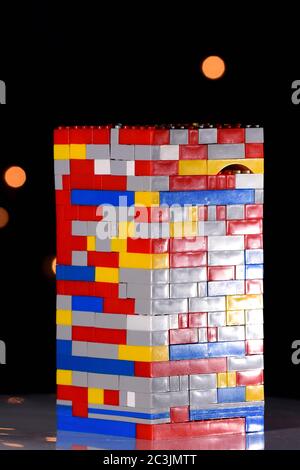 La forme de la tour est faite à l'aide de blocs de construction pour enfants et photographiée sur fond noir et bokeh Banque D'Images