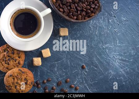 Une tasse de café avec des morceaux de sucre de canne, des biscuits au chocolat et un vase avec des grains de café. Vue de dessus Banque D'Images