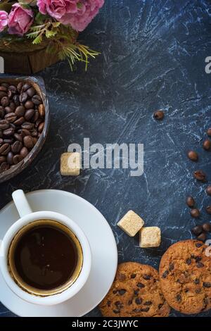 petit déjeuner de style vintage. Une tasse de café avec des morceaux de sucre de canne, des biscuits au chocolat et un vase avec des grains de café. Vue de dessus.version verticale Banque D'Images