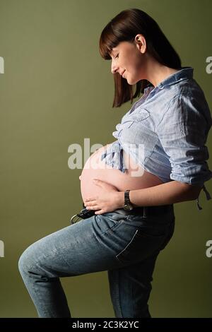 une jeune femme enceinte regarde son ventre et se prend avec ses mains Banque D'Images