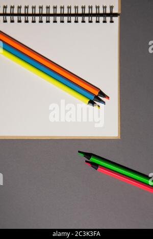 Ordinateur portable plat et crayons lumineux sur fond gris, vue du dessus Banque D'Images