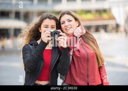 Des femmes qui utilisent un appareil photo numérique sans miroir dans une ville Banque D'Images