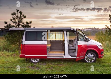 Saint-Pétersbourg, Russie - 22 juillet 2019 : Volkswagen Multivan California Ocean (transporteur), moderne couleur rouge et blanc. Est garée dans la forêt à vue du lever du soleil et portes ouvertes Banque D'Images