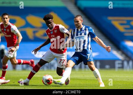 Brighton. 21 juin 2020. Bukayo Saka (front L) d'Arsenal défie Brighton et Neal Maupay de Hove Albion lors du match de la Premier League entre Brighton et Hove Albion et Arsenal FC au stade communautaire American Express de Brighton, en Grande-Bretagne, le 20 juin 2020. Crédit: Xinhua/Alay Live News Banque D'Images