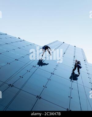 Photo à angle bas de deux personnes qui se rasent sur le côté d'un grand bâtiment Banque D'Images