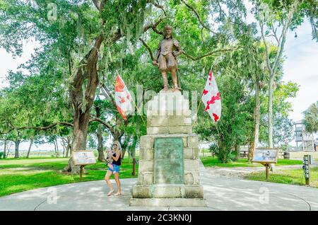 Une femme et son chien marchent devant une statue de bronze de Ponce de Leon à la fontaine de Pence de Leon du Parc archéologique de la jeunesse St. Augustine, Floride. Banque D'Images