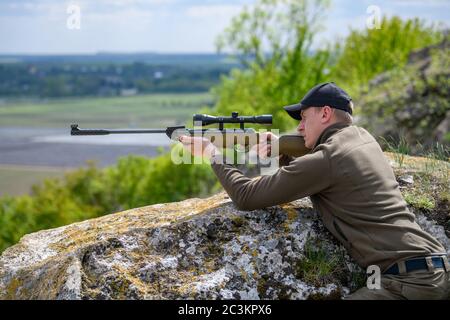 Fermer le mâle avec un pistolet en période de chasse. Hunter dans le camouflage vêtements nature fond Banque D'Images