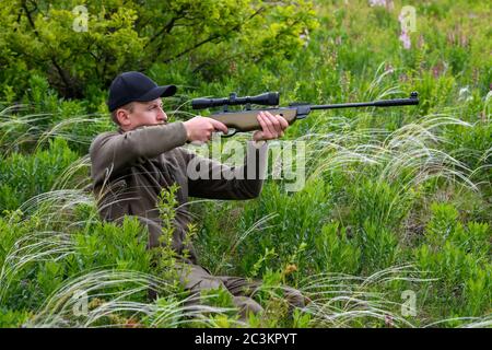 Fermer le mâle avec un pistolet en période de chasse. Hunter dans le camouflage vêtements nature fond Banque D'Images