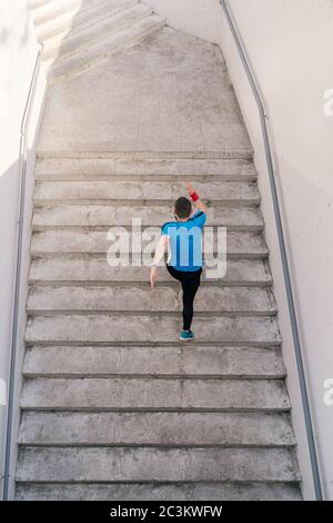 Jeune homme courant à l'étage dans les escaliers de la ville. Fitness, sport, personnes, exercice et concept de style de vie Banque D'Images