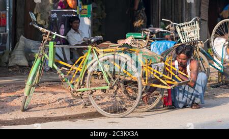 Sittwe, Etat de Rakhine, Myanmar - 15 octobre 2014 : homme réparant un taxi à vélo sur la route de Sittwe, la capitale de l'Etat de Rakhin au Myanmar. Banque D'Images