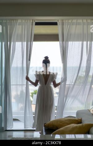 Gril thaïlandais le whirt robe ling code vestimentaire est debout en face de la chambre à coucher avec terrasse et piscine simming phanoramic sur la mer en face d'elle. Banque D'Images